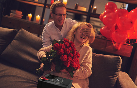 Image of man surprising a woman with romantic gift and flowers on their anniversary