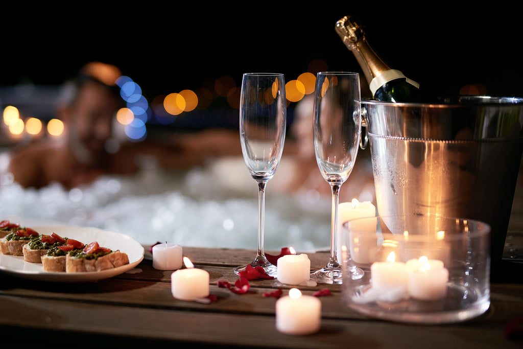 couple taking a romantic bath with champagne rose petals and candles