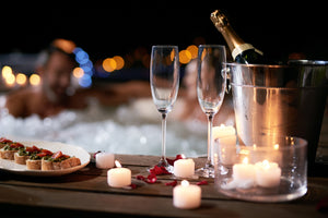 couple taking a romantic bath with champagne rose petals and candles