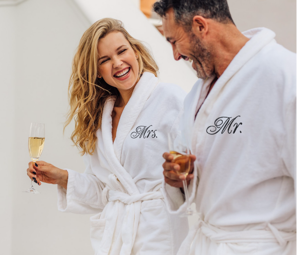happy couple enjoying champagne dressed in matching mr and mrs robes