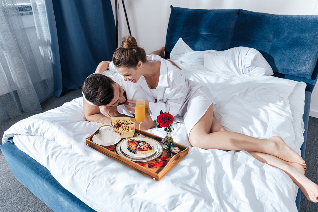 couple embracing and enjoying a beautiful breakfast in bed
