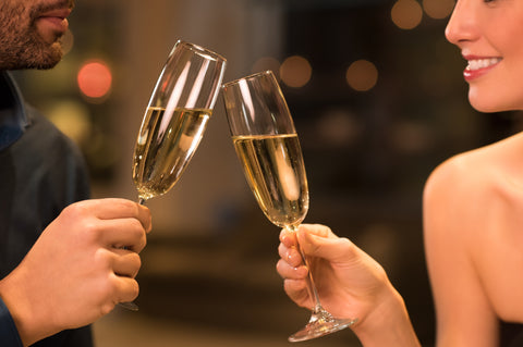 couple clinking champagne to celebrate their anniversary with romantic dinner